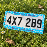 Personalized Turquoise Tropical Flowers license plate frame displayed on a plate outdoors