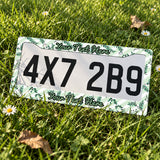 Personalized Green Botanical Leaves license plate frame displayed on a plate outdoors