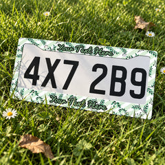 Personalized Green Botanical Leaves license plate frame displayed on a plate outdoors