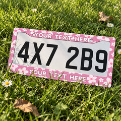 Personalized Pink Cherry Blossom license plate frame displayed on a plate outdoors