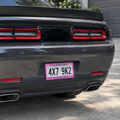 Pink Leopard Print license plate frame installed on a black sports car