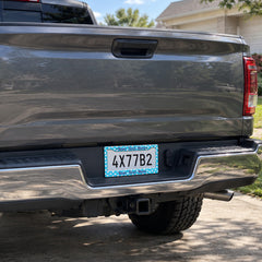 Turquoise Tropical Flowers license plate frame installed on a pickup truck